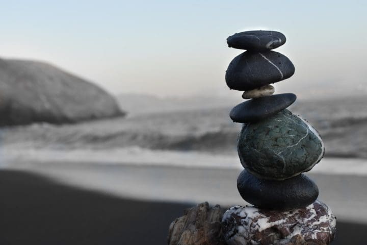 five small black rocks stacked precisely maintain work life balance